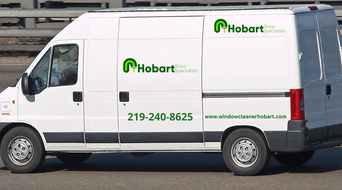 A white van featuring "hobbott," indicating a window cleaning service with a visible contact number for potential clients.