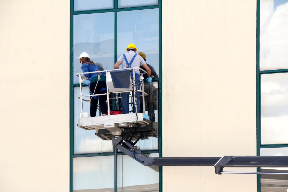 A professional window cleaner in London using a squeegee on a tall building's glass windows. 